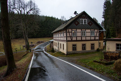 Road amidst trees and houses against sky in city