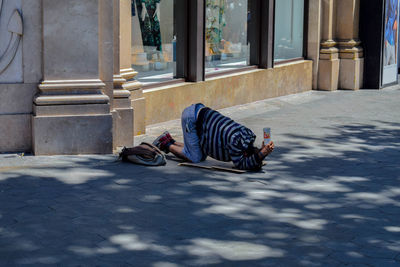 Man sleeping on street against building