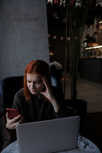 Frustrated woman using mobile phone in cafe