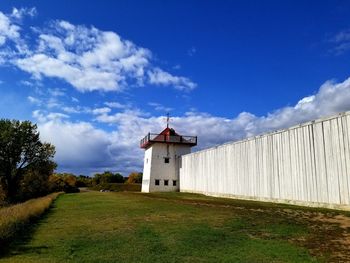 Tower on field by building against sky