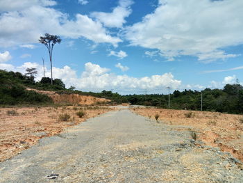 Dirt road amidst landscape against sky