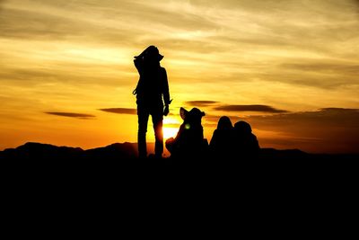 Silhouette people standing on land against sky during sunset