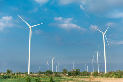 Windmills on field against sky