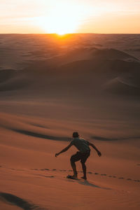 Rear view of man sandboarding at desert