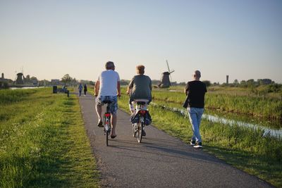 Rear view of people riding bicycle on road