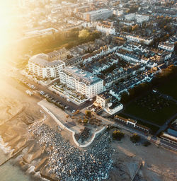 High angle drone view of street and worthing sea front amidst buildings at sunset