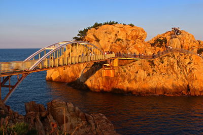 Footbridge by rock formation over sea