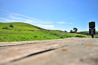 Surface level of road amidst field against sky