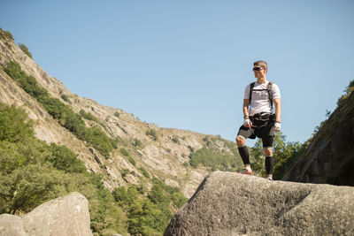 Full length of man standing on rock against sky