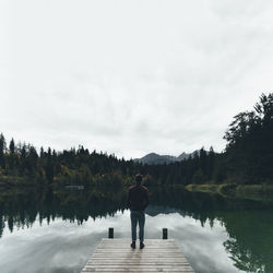 Rear view of man standing on lake against sky