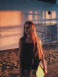 Portrait of young woman standing with skateboard