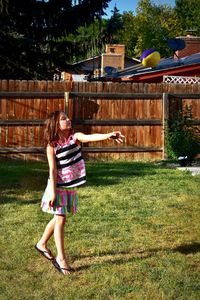 Full length portrait of smiling young woman in yard