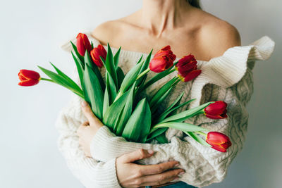 Midsection of woman holding red roses against white background