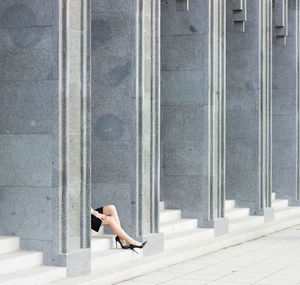 Low section of woman sitting on wall