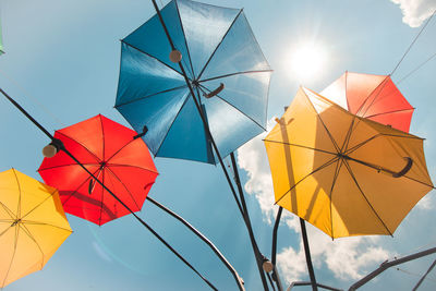 Low angle view of multi colored umbrellas hanging against sky