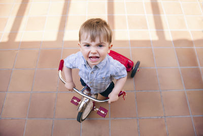 High angle portrait of boy riding bicycle on tiled floor