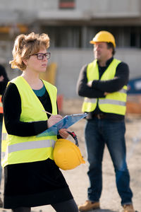 Engineer standing with clipboard at construction site