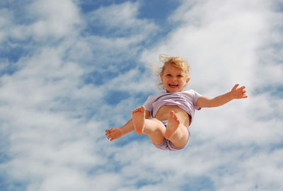 Low angle view of girl jumping against sky