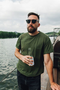 Man holding bottle while standing against sky