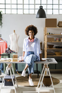 Businesswoman with headphones sitting on desk at studio