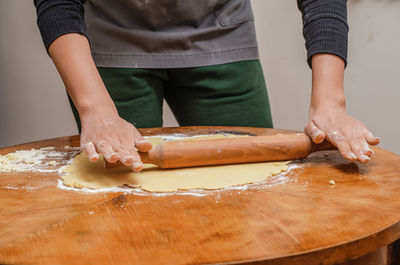 Rolling out cookie dough with a wooden splinter on table