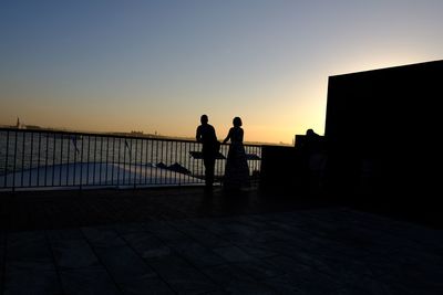 Silhouette people looking at sea during sunset