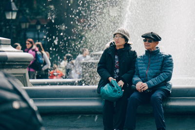 Friends sitting on wet car in city