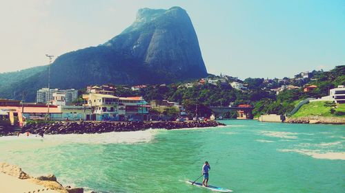 People on rock by sea against sky