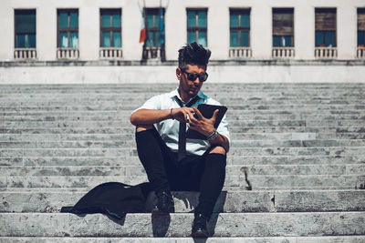 Full length of young man using mobile phone in city