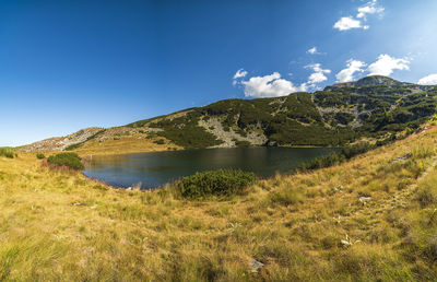 Scenic view of lake and mountains against blue sky