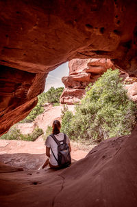 Rear view of woman sitting on rock