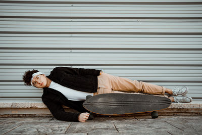 Full length of man sleeping on shutter against wall