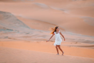 Full length of girl walking on sand dunes at desert