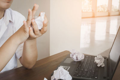 Midsection of woman holding paper while sitting on table