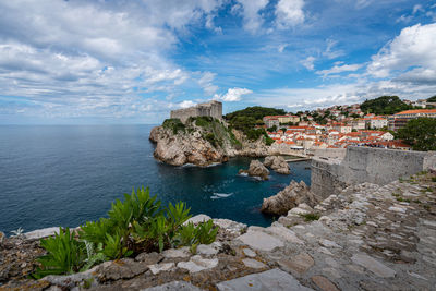 Buildings by sea against sky