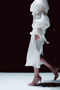 Elegant fashion details of white silky bridal dress, high heels. fashion model on black background