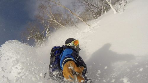 High angle view of man holding monopod while splitboarding on snowy mountain