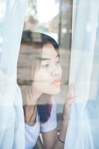 Portrait of woman looking through glass window