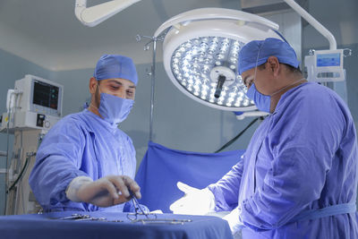 Side view of surgeons operating in room