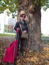 Full length of man standing by tree trunk during autumn