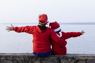 Rear view of mother and daughter enjoying christmas sitting on the bank of river