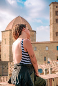 Woman sitting against buildings in city