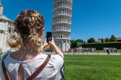 Rear view of photographer photographing against sky