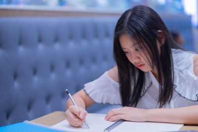 Midsection of woman reading book while sitting on table