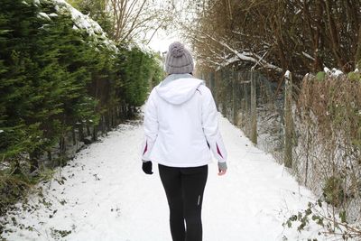 Rear view of woman walking on snow during winter