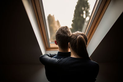 Rear view of man and woman looking through window