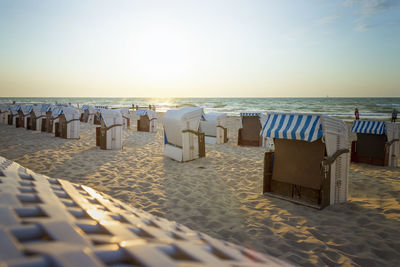 Hooded chairs on beach against sky