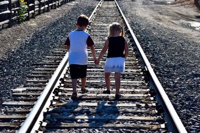 Rear view of people on railroad tracks