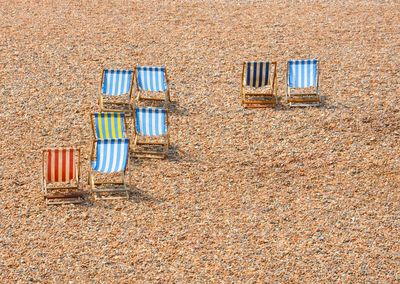 Multicoloured sun loungers on stoney beach in sun