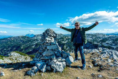 Man standing on rock against sky